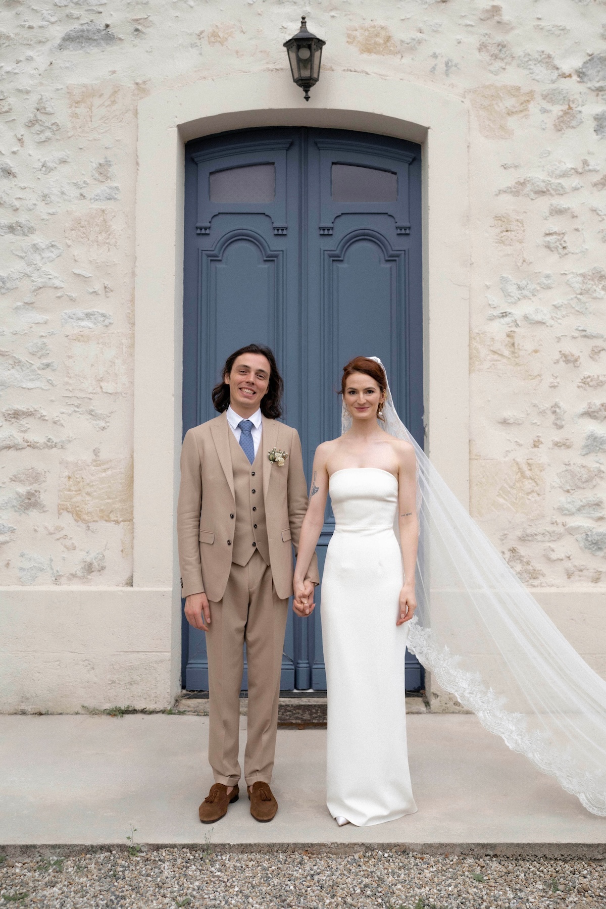 des mariés posent devant une porte bleue