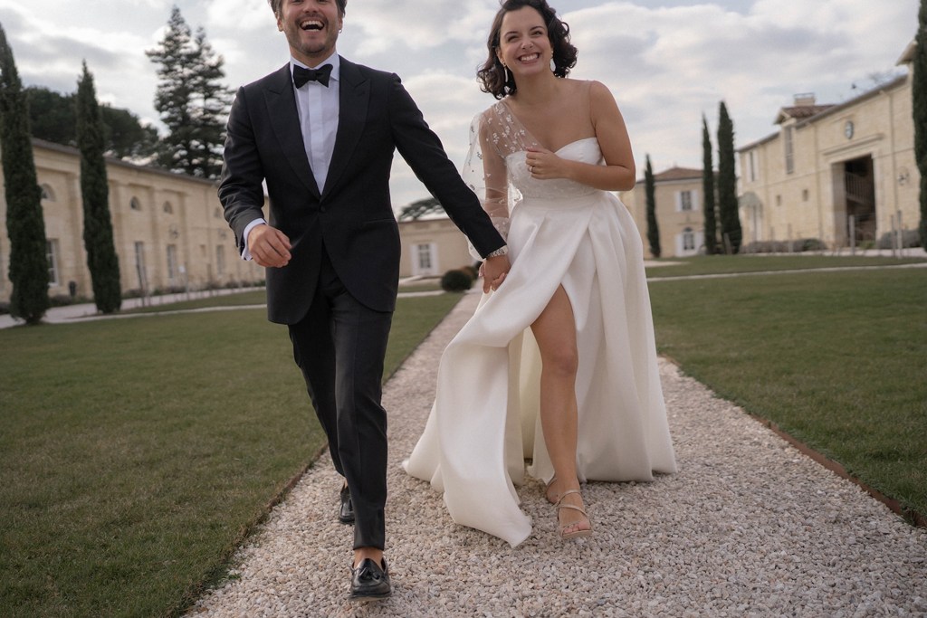 deux mariés courent vers l'appareil photo en riant